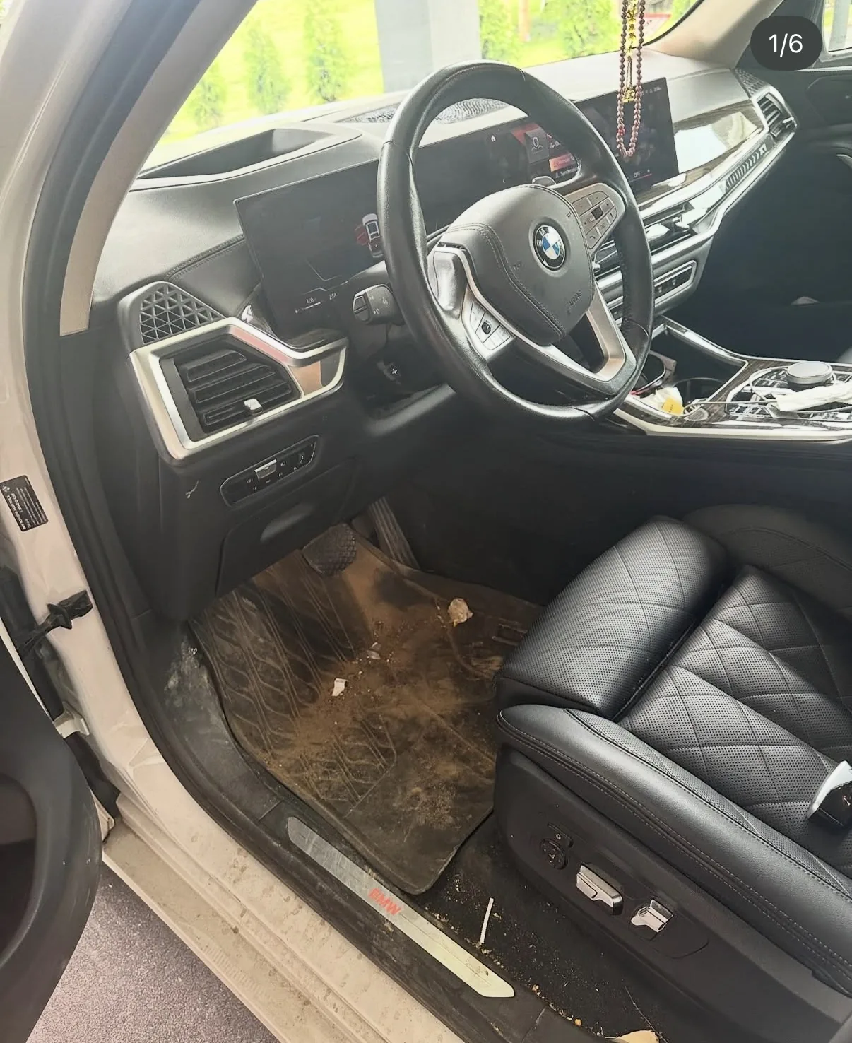 BMW interior before mobile detailing with dirt and debris on floor mat